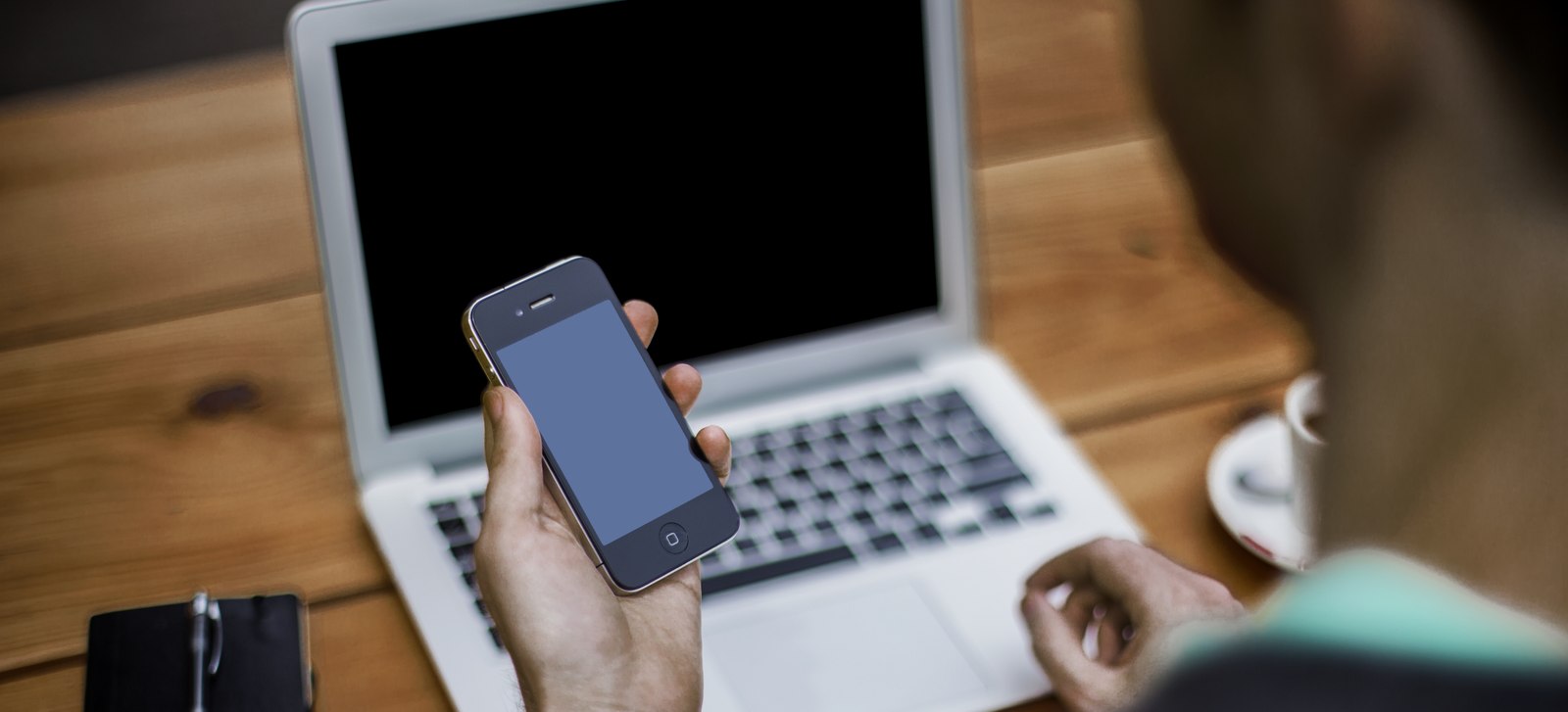 Man checking email on his phone next to an open laptop