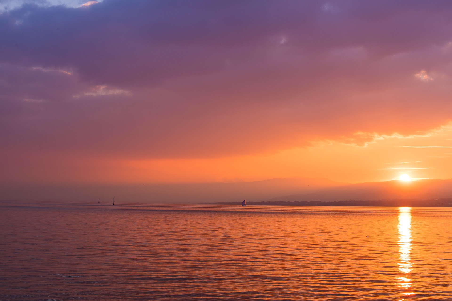 Purple and orange twilight sky over a calm ocean, sun reflecting on the water